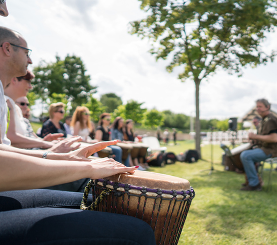 Groep mensen die deelnemen aan een percussie workshop bij Fun Beach Group Events in Panheel, Limburg.