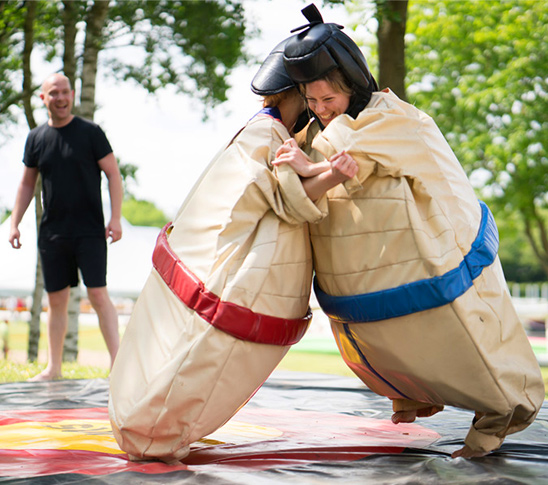 Twee dames die Sumo worstelen tijdens een personeelsuitje of bedrijfsuitje in Midden-Limburg.