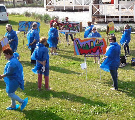 Allerlei mensen die deelnemen aan een graffiti workshop en hun eigen naam op een bord hebben gemaakt.
