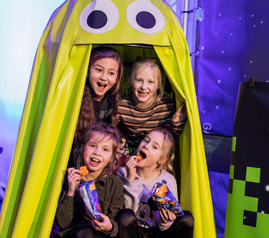 Kinderen zitten bij Pac-Man met Lays chips tijdens een kinderfeestje in de leukste arcadehal van Limburg.