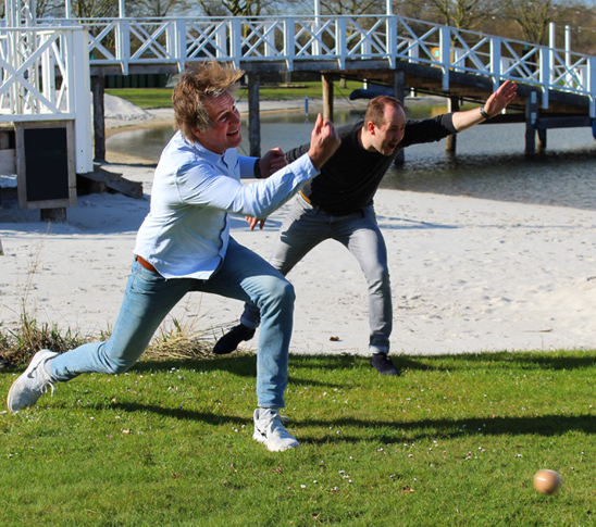 Een man die gaat klootschieten. Een spel dat lijkt op jeu de boules.