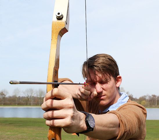 Jongen met een pijl en boog gaat boogschieten tijdens deze competitie.